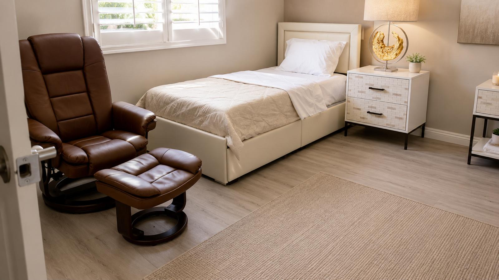 Bedroom with a plush recliner and ottoman beside the bed